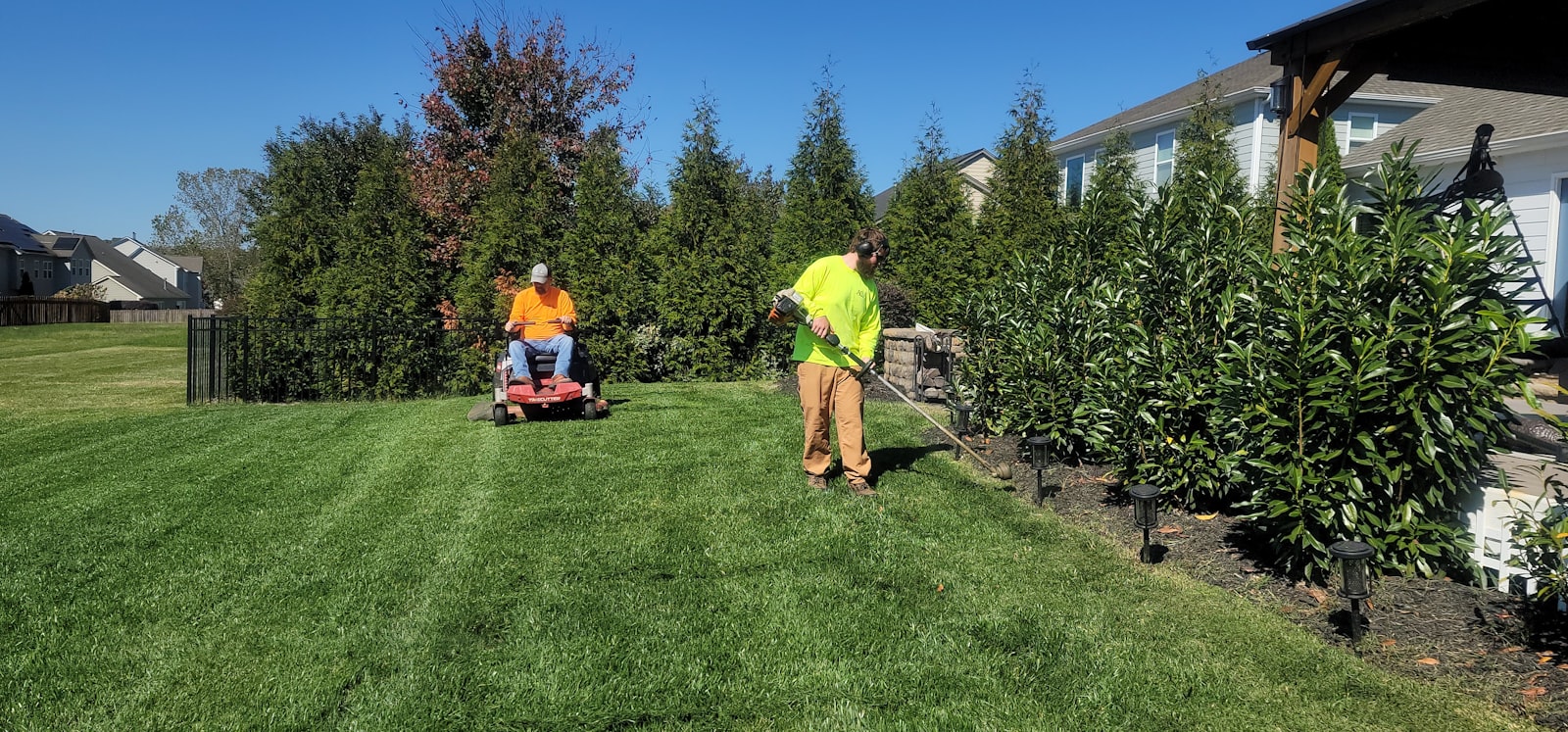 Crew mowing and trimming a suburban side yard