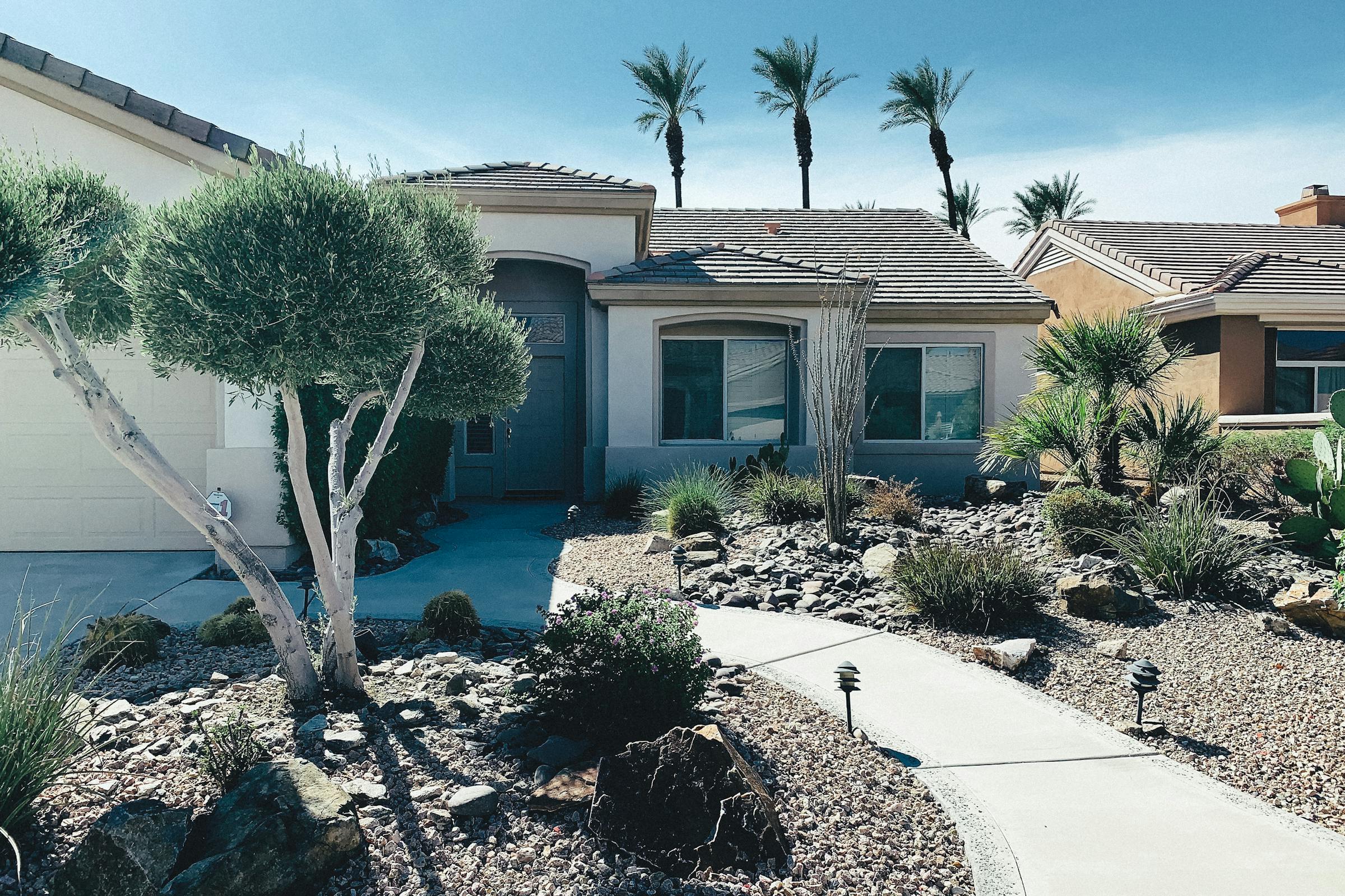 Desert front yard with gravel, palms, and a stucco house